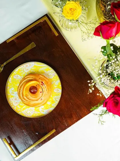 A top-down view of a styled tray with a pastry and flowers, creating an elegant flatlay.