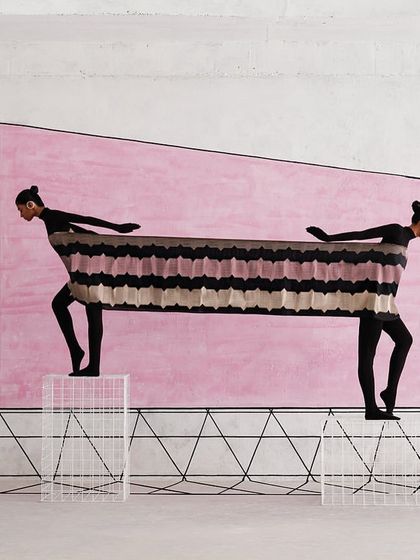 Two models are connected by a single piece of textile, creating a living sculpture. This conceptual image for Shanti Banaras explores connection and tension.