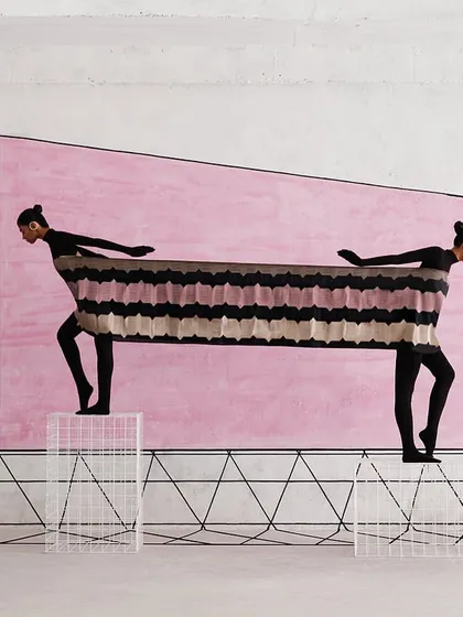 Two models are connected by a single piece of textile, creating a living sculpture. This conceptual image for Shanti Banaras explores connection and tension.