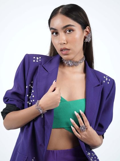 A model showcasing the full purple floral set, including choker, earrings, bracelet, and ring, styled with a modern blazer.