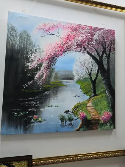 A beautiful painting can completely change the feel of a room. This serene landscape, with its soft light and blossoming cherry trees, brings a sense of peace and nature indoors, reflecting the kind of transportive art we love to connect our clients with.
