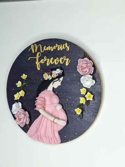 A closer look at the maternity wall art. The hand-sculpted flowers and the gentle posture of the mother-to-be are the main focus.