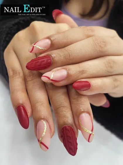 A cozy and unique design featuring a matte red "sweater" texture on accent nails. This is paired with a sheer nude base, red lines, and a touch of gold glitter for a stylish, autumnal look.