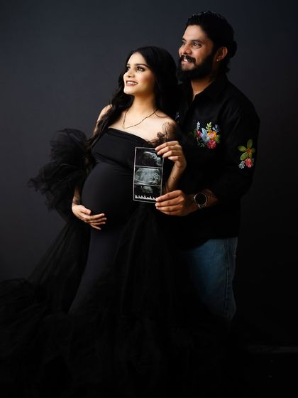The couple looks towards the future, holding up their baby's sonogram. This creative shot in their dark-themed maternity session is a beautiful announcement.