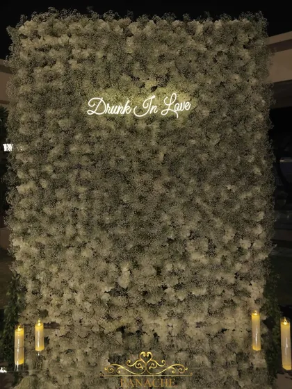 A "Drunk In Love" neon sign against a dense wall of white hydrangeas and baby's breath created the perfect modern and fun photo booth for the couple and their guests.