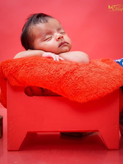 A peaceful portrait of the newborn sleeping on the red stool. Even without props, the vibrant color and soft texture create a beautiful image.