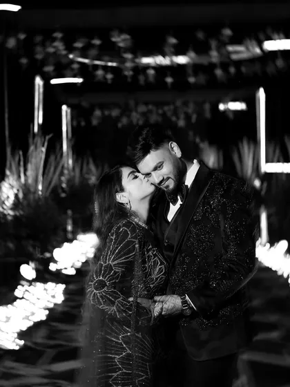 Stripping away the color reveals the raw emotion. This black and white portrait captures a tender kiss, with the dramatic lighting of the Sangeet walkway creating a timeless, intimate, and deeply romantic photograph.