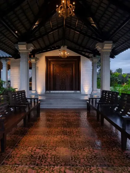 The grand entrance of the classical farmhouse, with an inviting porch furnished with traditional wooden benches.