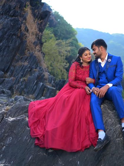 A quiet, romantic moment between a couple during their pre-wedding shoot on the rocks. The red gown and blue suit combination is a classic choice.