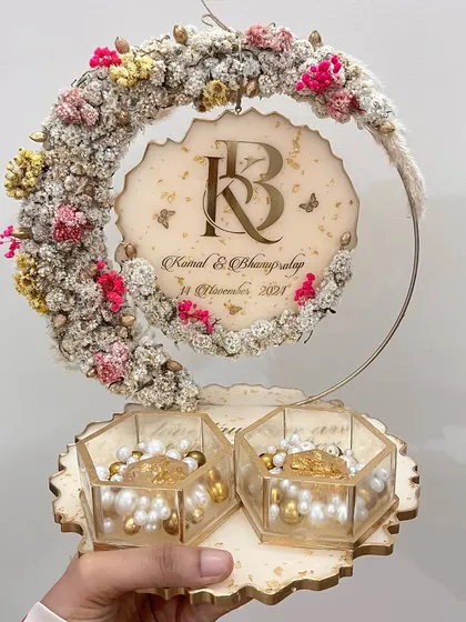 This elegant ring platter features a cream and pink floral hoop with hexagonal glass ring boxes. The couple's monogram is beautifully displayed on the hanging element.