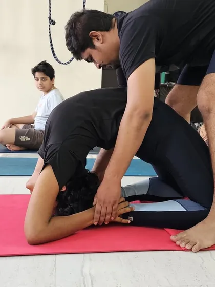 Providing an adjustment in Kapotasana. My hands guide the student to open her shoulders and lift her chest, protecting her lower back while deepening this intense backbend.