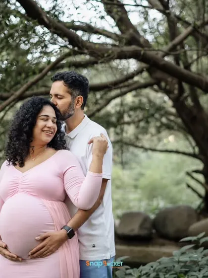 A sweet and simple portrait surrounded by nature. A kiss on the forehead is such a loving gesture, and the lush green trees make for a beautiful, natural frame.