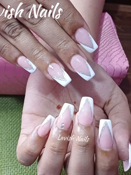 A sharp, modern V-shaped French manicure in white, outlined with silver glitter and accented with a single rhinestone.