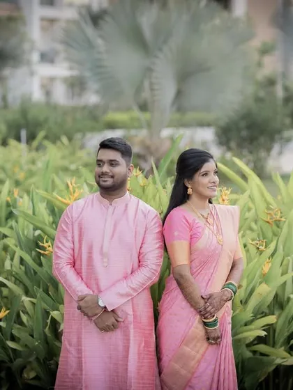A candid-style portrait of the couple looking in different directions, set in a lush garden.
