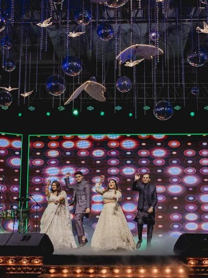 A wide shot of the bride and her brothers' performance, showcasing the grand stage and lighting.