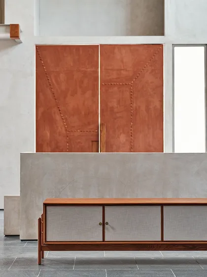 A custom-designed door at the Magari store, finished in an earthy red plaster with subtle stitched detailing, serves as a functional piece of art.