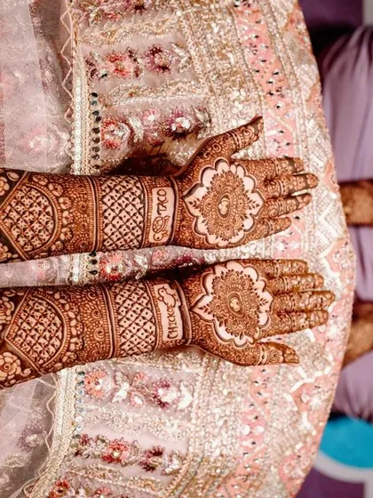 This top-down view shows a traditional design with a central floral mandala on each palm, surrounded by detailed jaali and band work on the arms.