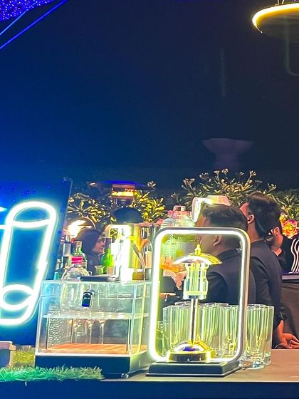 A vibrant rooftop party setup with a "Shots Bar" neon sign. We can create dedicated stations for different types of drinks to enhance guest flow and experience.