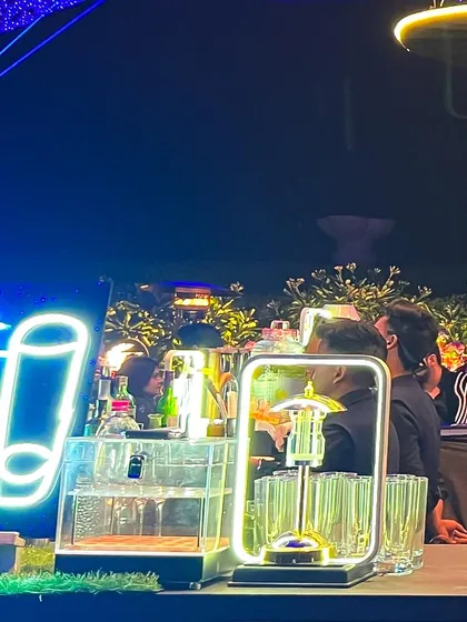 A vibrant rooftop party setup with a "Shots Bar" neon sign. We can create dedicated stations for different types of drinks to enhance guest flow and experience.