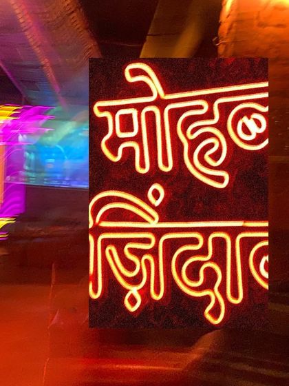 A blurry, energetic shot of a Hindi neon sign, capturing the dynamic nightlife of Delhi.