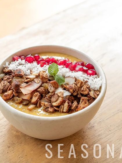 A beautiful shot of our seasonal smoothie bowl, showcasing the vibrant colours of mango, pomegranate, and fresh mint. It's a bowl of pure sunshine.