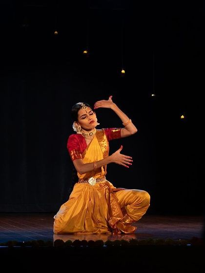 My student performing on stage during her Rangapravesham. The lighting highlights her expressive form as she sits in a posture of storytelling.