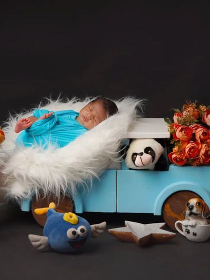 All aboard for a dreamy adventure. This newborn is tucked into a fluffy blue truck prop, surrounded by a delightful audience of stuffed safari animals.