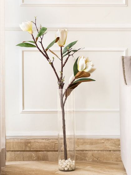 A single, elegant stem of artificial white magnolia. Its simplicity is its strength, making it a perfect minimalist statement in a tall, clear glass vase for a touch of modern sophistication.