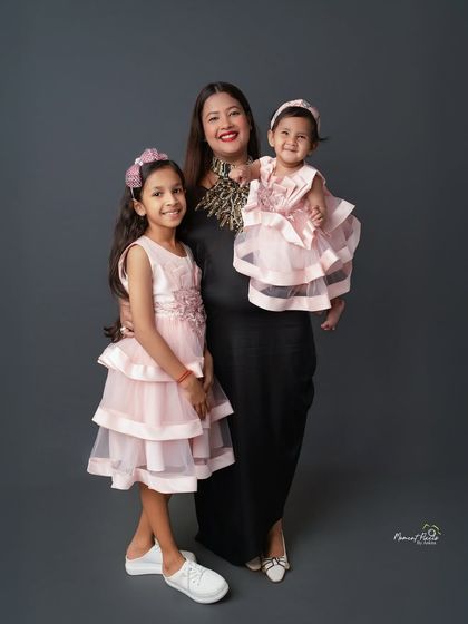 A trio of grace, giggles, and glam. This beautiful portrait of a mother with her two daughters, all dressed in lovely pink, is a testament to their special bond.