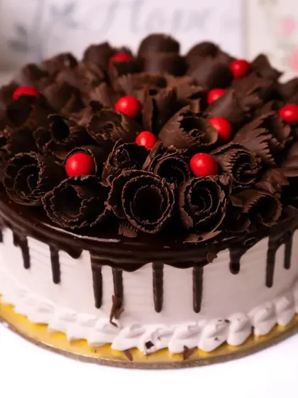 This is our classic Black Forest cake, a timeless favorite. Layers of moist chocolate cake, whipped cream, and cherries are topped with beautiful chocolate shavings and a glossy drip.