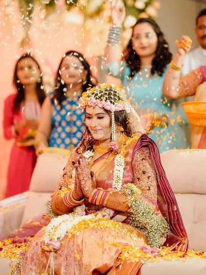 A bride during her Haldi ceremony, showered with flowers and wearing our floral headpiece.