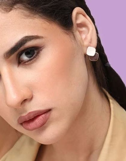 A close-up model shot of the classy minimal drop earrings, featuring a two-tone brown and white design.