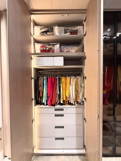 A tall, single-section wardrobe organized for maximum efficiency. We used the upper shelves for seasonal items stored in protective bags, with frequently worn clothes hanging below, and drawers for smaller folded items.