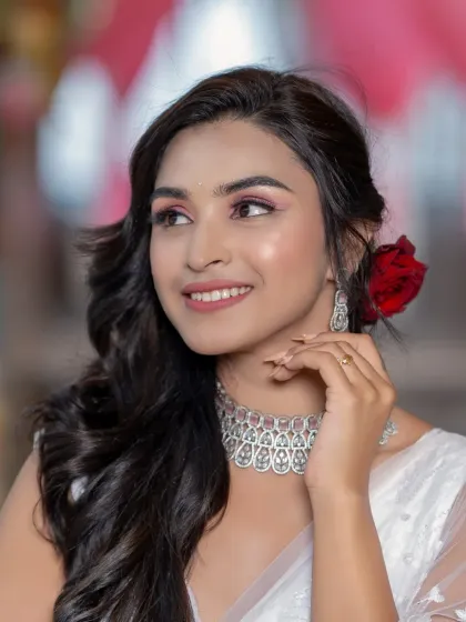 A beautiful smile that lights up her face. The red rose in her hair adds a pop of color to the all-white look.