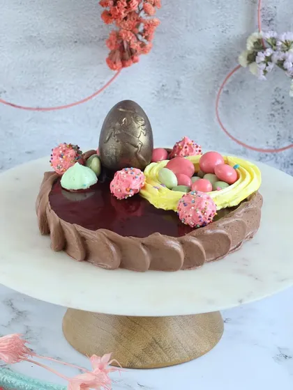 This heart-shaped Easter cake is a unique seasonal offering, topped with a chocolate egg and a nest of candy eggs.