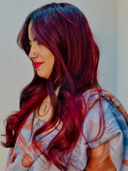 A happy client showing off her new cherry red hair. The color brightens up her whole look.