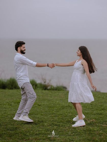 A playful dance on the green grass overlooking the water. This shot is full of life and movement, showcasing the couple's joyful connection.