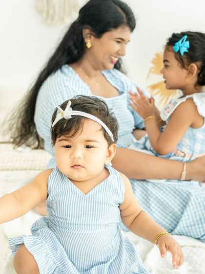 A beautiful moment between a mother and her two daughters. The baby looks curiously at the camera while mom shares a smile with her older girl.