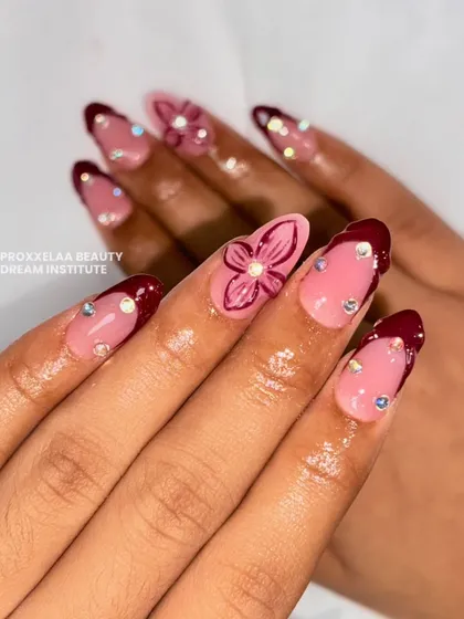 This view highlights the floral accent nail and the precise placement of the crystals on the maroon-tipped nails, creating a cohesive and elegant look.