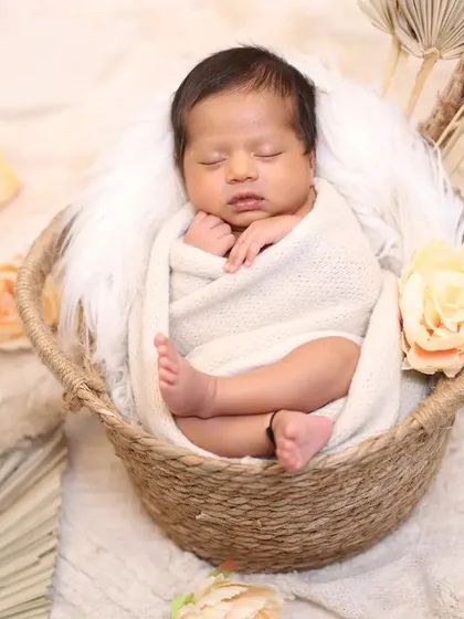 A classic newborn pose, this image shows a baby swaddled comfortably in a rustic woven basket. I use soft, neutral tones and natural textures like faux fur and dried florals to create a warm and organic feel for the portrait.