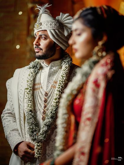 A creative portrait using focus to highlight the groom. The bride is softly blurred in the foreground, creating an artistic composition that feels like a still from a movie.