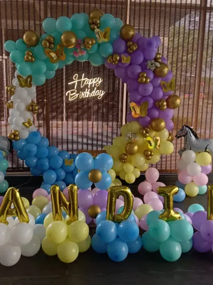 A unique horse or pony-themed first birthday. This setup features a colorful balloon ring, horse-shaped foil balloons, a light-up number '1', and the name "NANDIKA" spelled out in balloon letters.