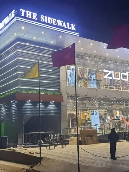 Another view of 'The Sidewalk' after its completion, with flags marking its opening. This image captures the building's strong presence on the street, fulfilling its role as a commercial hub.