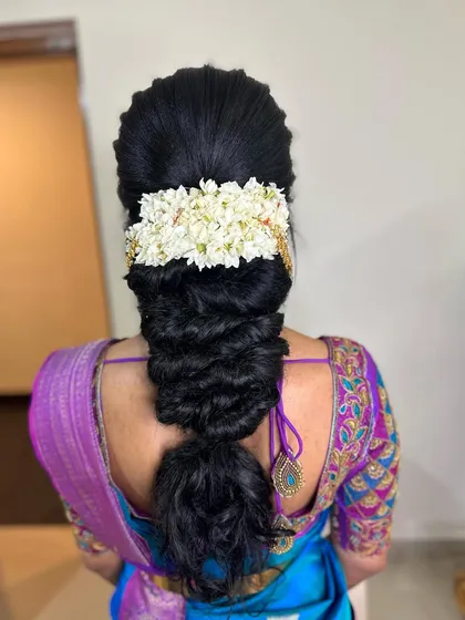A voluminous messy braid for a 'Varpooja' look. The addition of a jasmine veni keeps the style traditional while the texture adds a modern touch.