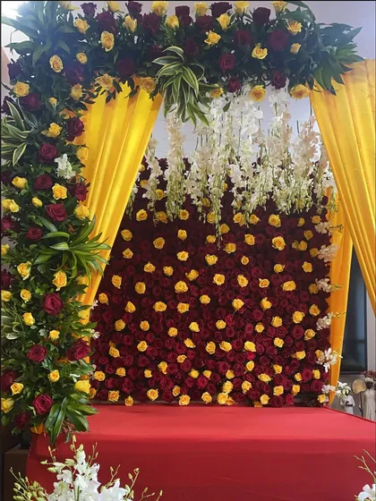 A vibrant and rich floral display for Ganpati, featuring a dense wall of fresh roses and elegant orchids.