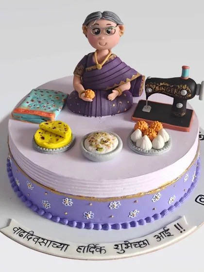 A beautiful custom cake for a mother's birthday, featuring her favorite things. I included a miniature sewing machine, her favorite Maharashtrian sweets like puran poli and modak, and a figurine wearing a saree.