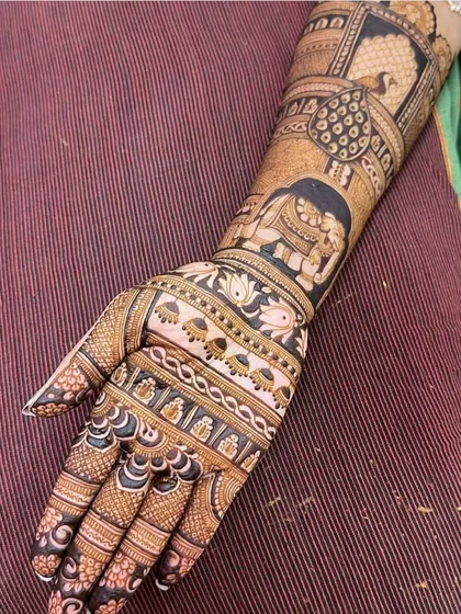 A single arm view of a detailed bridal design. This pattern includes elephants, peacocks, and lotus flowers, all classic symbols of a traditional Indian wedding.