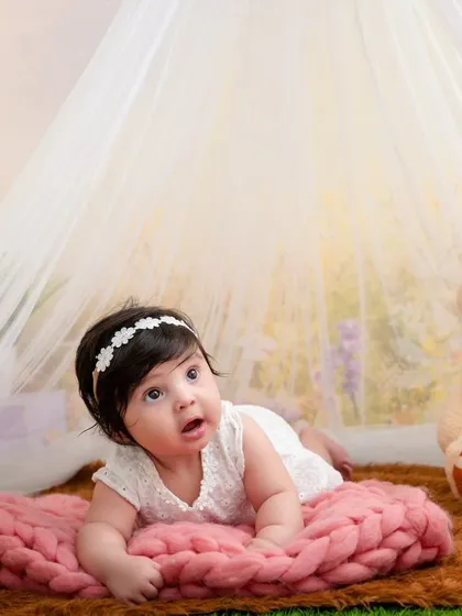 A precious tummy-time portrait of a four-month-old baby girl, looking up with wonder and curiosity.