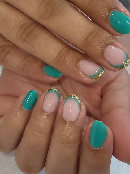 A double French manicure on natural nails. This design features a teal tip with a fine line of gold glitter along the smile line for a modern and chic look.
