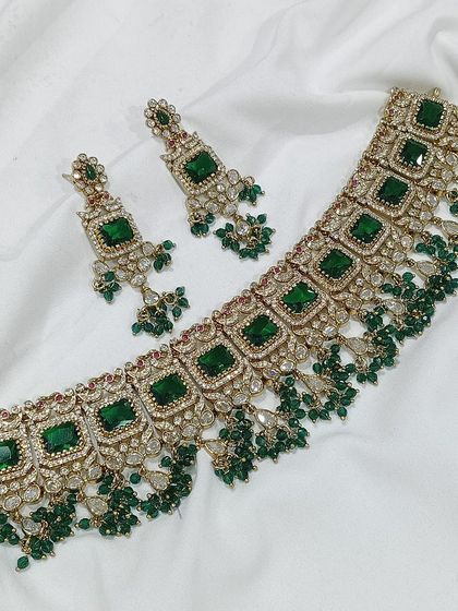 A popular choker design featuring square-cut stones, available in a variety of colors like emerald green, white, aqua blue, and baby pink. The matching earrings complete this elegant and modern ethnic set.